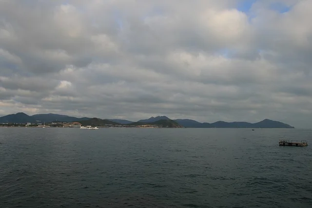 Hainan adasında Sanya, Dadonghai'den bulutlu havada deniz ve karşı kıyı görünümü.